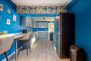 a kitchen with blue walls and a black refrigerator at Room 3 plus optional additional lounge area with double sofa bed, 23 Deganwy Avenue in Llandudno
