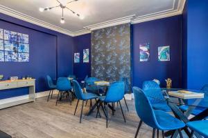 a dining room with blue chairs and a table at Room 3 plus optional additional lounge area with double sofa bed, 23 Deganwy Avenue in Llandudno