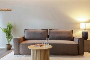 a brown couch in a living room with a table at Modern Easy-Access 1BR Apartment in Midtown in Aarhus