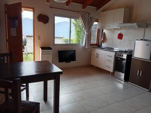 a kitchen with a table and a refrigerator and a table at La Fortaleza Deptos in Villa Traful