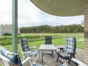 3 Stühle und ein Tisch auf einer Veranda mit Blick auf ein Feld in der Unterkunft Apartment in Julianadorp near the Beach in Julianadorp