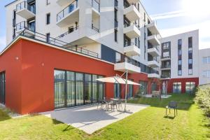 an apartment building with a red facade and a patio at Zenitude Hôtel-Résidences Le Havre Les Docks in Le Havre