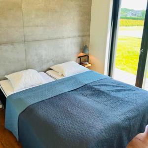 a bedroom with a blue bed with a large window at FF1005 Luksus sommerhus med havudsigt i Hejlsminde in Hejls