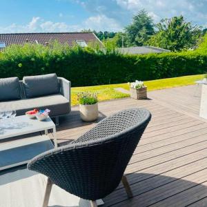 a wicker chair sitting on a wooden deck at FF1005 Luksus sommerhus med havudsigt i Hejlsminde in Hejls