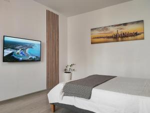 Un dormitorio con una cama y un televisor en la pared. en Sunset Bucharest, en Bucarest
