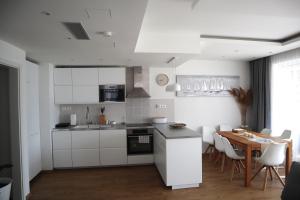 a kitchen with white cabinets and a wooden table at Fehér Lótusz Csopak in Csopak