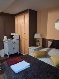 a bedroom with a bed and a dresser with a microwave at Chambre dans le centre historique in Pont-Audemer