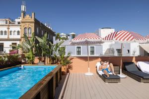Dos personas sentadas en una silla en un balcón junto a una piscina. en The Loft House Sevilla, en Sevilla 49 fotos más