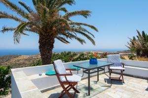 a patio with a table and chairs and a palm tree at VORINI'S HOUSE, Exampela,Sifnos in Katavatí