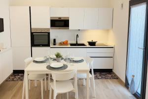 a white kitchen with a white table and chairs at Casa Orchidee 9 in Elmas
