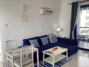 a living room with a blue couch and a table at paphos pool view gem - cozy 1 bed Apartment in Paphos