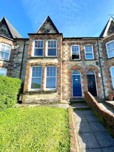 a brick house with a blue door and a yard at Truro City with Views Ground Floor Apartment in Kenwyn