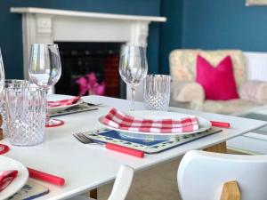 a white table with red and white plates and wine glasses at Truro City with Views Ground Floor Apartment in Kenwyn