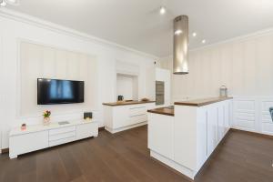 a kitchen with white cabinets and a flat screen tv at Divon Luxury Apartments by Wawel Castle in Kraków