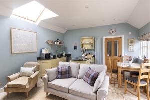 a living room with a couch and chairs and a kitchen at The Heritage Cottage in Swinton