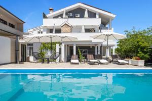 a villa with a swimming pool in front of a house at Apartments 1 with pool and private jacuzzi in Vodice
