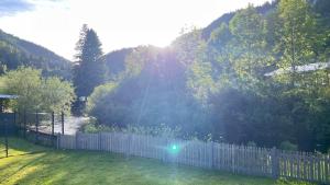 a white fence in a yard with trees and a river at Maison au cœur du Val-de-Travers in Saint-Sulpice