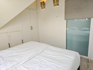 een slaapkamer met een wit bed en een raam bij Studio het Strandhuis KA05 in Vlissingen