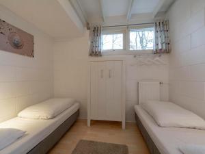 two beds in a small room with a window at Holiday Home near Sint Maartenszee Beach in Sint Maartensvlotbrug
