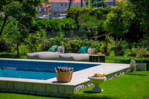 een zwembad in een tuin met stoelen en een bank bij Heritage Villa Baković in Dubrovnik