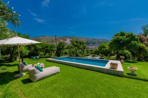 een achtertuin met een zwembad en een parasol bij Heritage Villa Baković in Dubrovnik +80 foto's