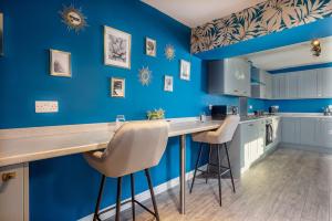 a kitchen with blue walls and a counter with stools at Room 8 ,double room with private bathroom with optional additional single room room 7 for third guest, 23 Deganwy Avenue in Llandudno