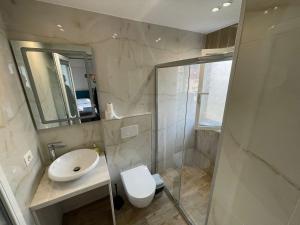 Un baño con lavabo, inodoro y ducha. en Boutique Central Studio Apartments, en Tirana