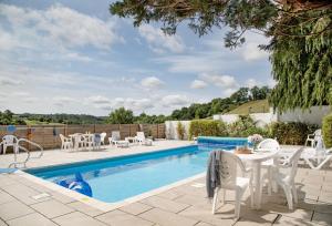 a swimming pool with white chairs and a table next to it at Fernwood in Totnes