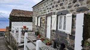 a stone house with white windows and a white fence at Refúgio do Sossego in Pedreira