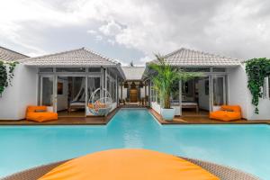 a swimming pool in a villa with orange furniture at Villa Cemacase in Cemagi
