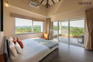 a bedroom with a large bed and large windows at EKOSTAY - Casa Den in Igatpuri +26 photos