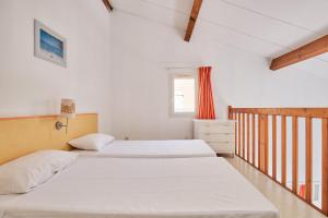 Dos camas en una habitación con paredes blancas y una ventana. en Résidence Odalys Le Grand Bleu, en Vendres-Plage 46 fotos más