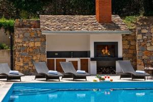 a swimming pool with chairs and a fireplace at Villa Mosor Mit Beheiztem Salzwasserpool Und Sauna in Omiš