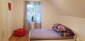 a room with a bed with a window and a red stool at Großer Stern in Stoltebüll
