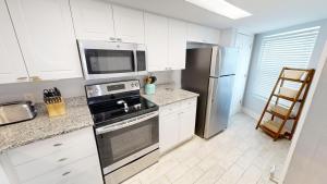 a kitchen with white cabinets and a stainless steel refrigerator at SeaCrest 212 in Fort Walton Beach +41 photos
