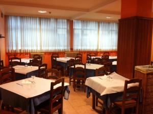 a dining room with white tables and chairs and windows at Hotel Valle de Ayala in Llodio