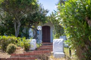 a house with a red door and some trees at AHR Altura Hotel Porto Rafael in Palau
