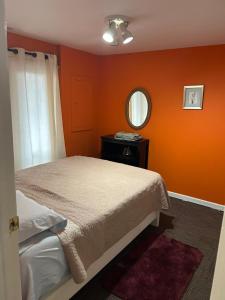 赫恩登8 mins to Dulles Airport Suite的一间卧室设有橙色的墙壁、一张床和镜子 更多7张照片