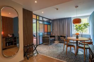 Una sala de estar con una mesa y un espejo. en ProfilHotels Aveny, en Umeå