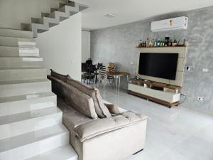 ein Wohnzimmer mit Couch und Fernseher in der Unterkunft Casa em Boiçucanga com 2 suítes, piscina e sauna integrada in São Sebastião