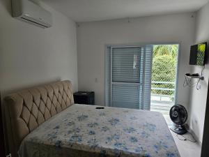 ein Schlafzimmer mit einem Bett und einer Glasschiebetür in der Unterkunft Casa em Boiçucanga com 2 suítes, piscina e sauna integrada in São Sebastião + 35 Fotos