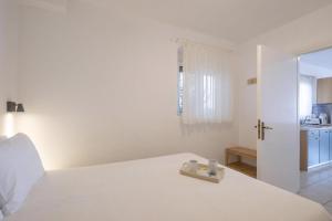 a white bedroom with a bed with a tray on it at Ferienwohnung Zesa Mit Balkon Und Meerblick in Kivérion