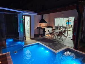 ein Haus mit Swimmingpool mit Küche und Tisch in der Unterkunft Casa em Boiçucanga com 2 suítes, piscina e sauna integrada in São Sebastião