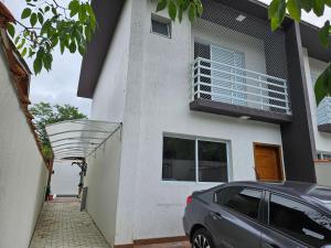 ein vor einem Gebäude mit Balkon geparktes Auto in der Unterkunft Casa em Boiçucanga com 2 suítes, piscina e sauna integrada in São Sebastião