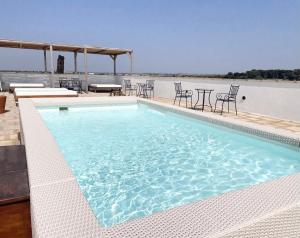 a swimming pool with chairs and tables on a building at Masseria Vico in Villaggio Resta
