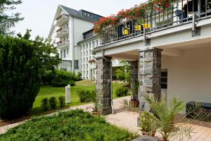 a building with a balcony with flowers on it at Vitalhotel Weisse Elster in Bad Elster