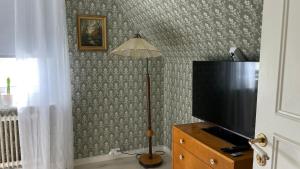 a living room with a television and a lamp at Villa ASTRID PremiumFerienhaus inkl Bettwäsche Handtücher in Storebro