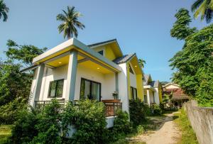 una casa amarilla con una palmera en el fondo en Honey Moon House - Nature & Serenity - Near Aum Yoga - 4K SmartTV, en Ko Pha Ngan