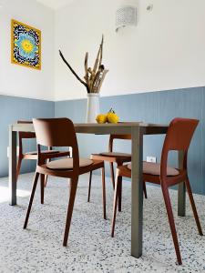 - une table à manger avec des chaises et un vase avec des fruits dans l'établissement Dimora Azzurra, à Santa Marinella
