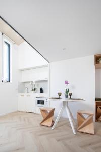 eine weiße Küche mit einem Tisch und Stühlen in der Unterkunft T0 do Carril, Aveiro in Aveiro